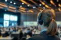 An interpreter wearing a headset translates simultaneously in a bustling conference room filled with attendees. The Royalty Free Stock Photo