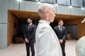 interracial bodyguards in suits protecting senior