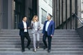 Senior gray-haired man, young asian man and one businesswoman walking near the office, talking Royalty Free Stock Photo