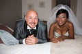 interracial couple african caucasian american bride and groom lying on bed at home in wedding