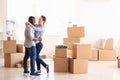 Interracial couple with carton boxes in room. Moving into new house