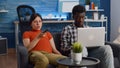 Interracial couple expecting child sitting together on couch Royalty Free Stock Photo