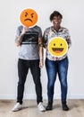 Interracial couple holding an expressive emoticon face facial expression frown and smile relationship issue concept Royalty Free Stock Photo