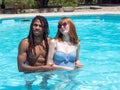 Interracial couple in love, play in the pool. The girl very white and red hair and the boy black Royalty Free Stock Photo