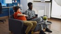 Interracial couple of parents expecting baby sitting on sofa Royalty Free Stock Photo