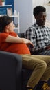 Interracial couple of parents expecting baby sitting on sofa Royalty Free Stock Photo