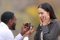 Interracial couple proposing marriage in a park