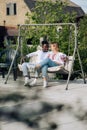 Interracial couple sits on bench swing in garden dressed in Ukrainian embroidered shirts