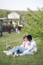 Interracial couple sits on grass in spring garden dressed in Ukrainian embroidered shirts