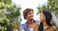 Interracial, couple and smile together in nature, happy and love in diversity people with tree in backyard. Happiness Royalty Free Stock Photo