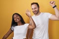 Interracial couple standing over yellow background dancing happy and cheerful, smiling moving casual and confident listening to Royalty Free Stock Photo