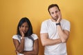 Interracial couple standing over yellow background thinking looking tired and bored with depression problems with crossed arms Royalty Free Stock Photo