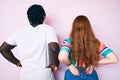 Interracial couple wearing casual clothes standing backwards looking away with arms on body