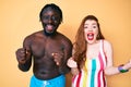 Interracial couple wearing swimwear celebrating surprised and amazed for success with arms raised and open eyes