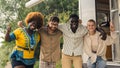 Interracial friendship on a camping van trip. Diverse people, four close friends hugging, smiling, showing a thumb up Royalty Free Stock Photo