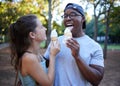 Interracial, ice cream or couple of friends in a park walking on a fun romantic date in nature bonding together. Romance Royalty Free Stock Photo