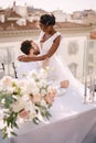 Interracial wedding couple. Destination fine-art wedding in Florence, Italy. An African-American bride sits on her