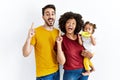 Interracial young family of black mother and hispanic father with daughter smiling amazed and surprised and pointing up with