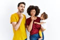 Interracial young family of black mother and hispanic father with daughter thinking concentrated about doubt with finger on chin Royalty Free Stock Photo