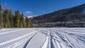 Intersecting tire tracks are visible on the snow-covered surface of the frozen lake. Royalty Free Stock Photo