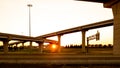 Intersection of elevated highway at sunset with bright sunset shining thru pillars