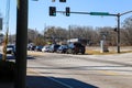 An intersection on the street with traffic signals turned green and parked cars along the street with bare and brown winter trees Royalty Free Stock Photo