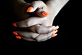 Intertwined girl's hands with orange false nails