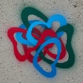 Intertwining loops of blue, red, and green spray paint create a complex knot design on