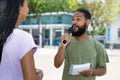 Interview of african american male tv journalist with famous person outdoor in city