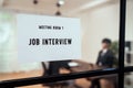 Interview sign in front of the meeting room. Business people sit at a table and wait for company Human ResourceHR.