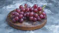 Intimate Portrait: Vibrant Red Grapes Captured on a Sleek Round Board Against a Subtle Gray Backdrop