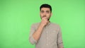 Intimidated scared brunette man looking frightened and covering mouth with hand. green background, chroma key