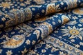 Intricate blue and gold paisley fabric with ornamental patterns on rolled textile Royalty Free Stock Photo