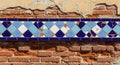 Intricate blue and white diamond pattern ceramic tile border on textured brick wall Royalty Free Stock Photo