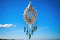 intricate glass wind chime hanging against a clear blue sky