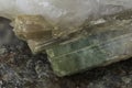 Intricate view of green tourmaline crystals with distinct striations, embedded in translucent quartz, showcasing geological beauty