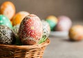 Intricately designed Easter eggs in a woven basket on rustic surface. Royalty Free Stock Photo