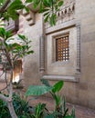 Intricately designed rustic wrought iron window grill adorns a weathered brick wall, adding a touch of old world charm