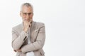 Intrigued and pleased good-looking old male with white beard and moustache in black frames and elegant suit holding hand