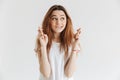 Intrigued woman praying with crossed fingers and looking away Royalty Free Stock Photo