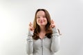 Intrigued woman in t-shirt praying with crossed fingers and looking away over grey background Royalty Free Stock Photo