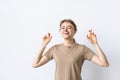 Young woman in t-shirt praying with crossed fingers and looking away over grey background Royalty Free Stock Photo