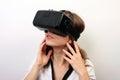 Intrigued woman in a white formal shirt, wearing Oculus Rift VR Virtual reality 3D headset, exploring a game