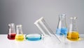 Laboratory glassware with colorful liquids on white table against grey background Royalty Free Stock Photo