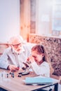 Intriguing girl considering microelement in microscope at home