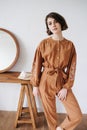 Intriguing woman possing for a photo in a brown jumpsuit