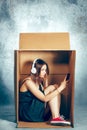 Introvert concept. Woman sitting inside box and working with phone Royalty Free Stock Photo