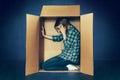 Introvert concept. Woman sitting inside box and working with phone Royalty Free Stock Photo