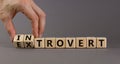 Introvert or extrovert symbol. Hand turns cubes and changes the word `introvert` to `extrovert`. Beautiful grey background, co Royalty Free Stock Photo