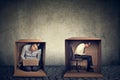 Introverts. Man and woman sitting inside boxes working on laptop